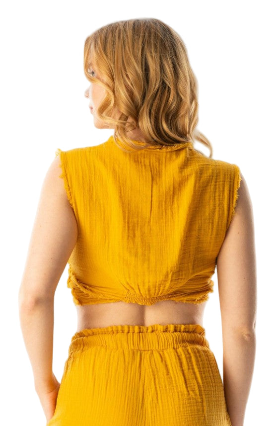 Woman wearing a mustard yellow sleeveless top and shorts on a white background