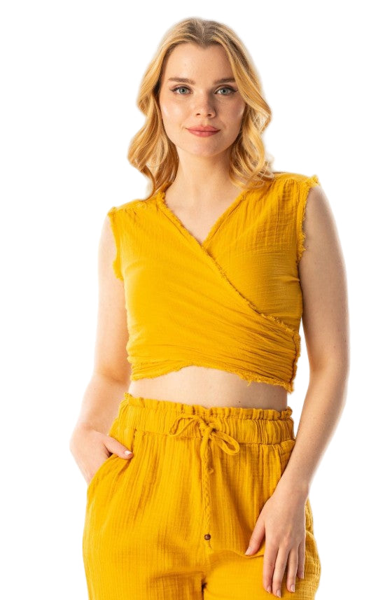 Woman wearing a yellow sleeveless top and pants on a white background