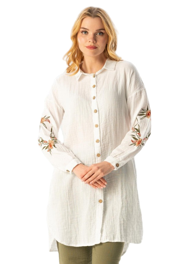 Woman wearing a white long-sleeve shirt with floral embroidery on a white background